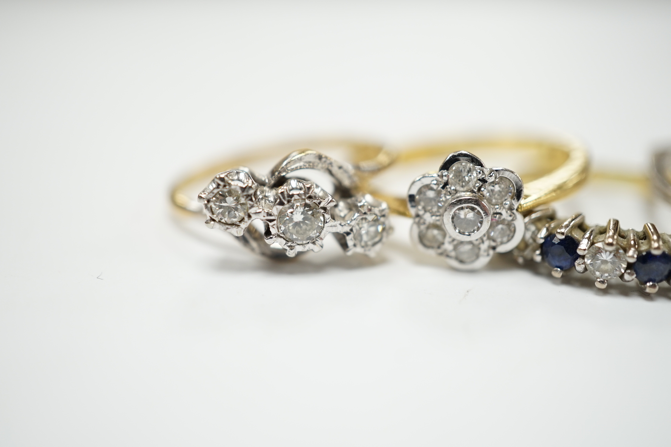 Four assorted 18ct and diamond set rings, including solitaire, flower head cluster, three stone crossover and seven stone half hoop, together with and 18ct sapphire and diamond set half hoop ring, gross weight 15.6 grams